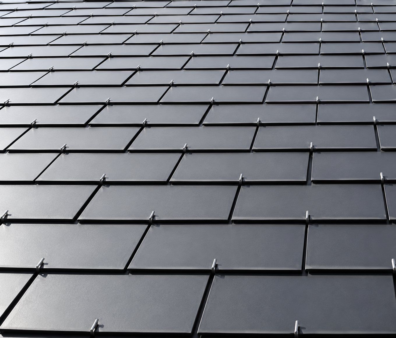 Gros plan sur une toiture couverte d'ardoises gris foncé rectangulaires disposées en rangées bien alignées.